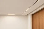 Матовый натяжной потолок с линейным светильником, утопленным в нишу, и дверью из дуба